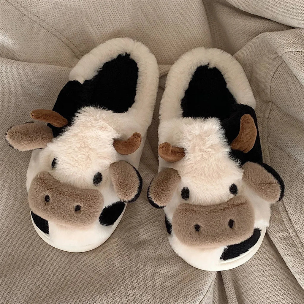 White cartoon cow design faux fur slippers for women with a non-slip textured sole.