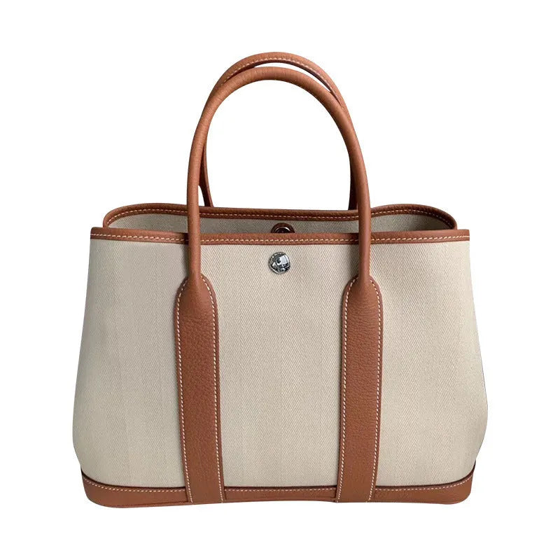 Women's canvas bucket tote bag with leather straps in black, shown with crossbody carry.