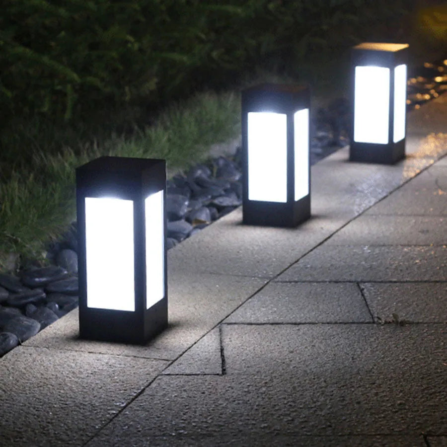 Set of solar-powered waterproof garden lights installed along a lawn edge and on a wall.