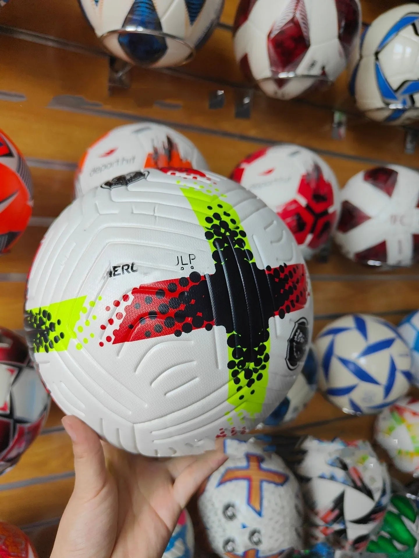 Fluorescent green Size 5 football with seamless thermal adhesive patches on a green pitch.
