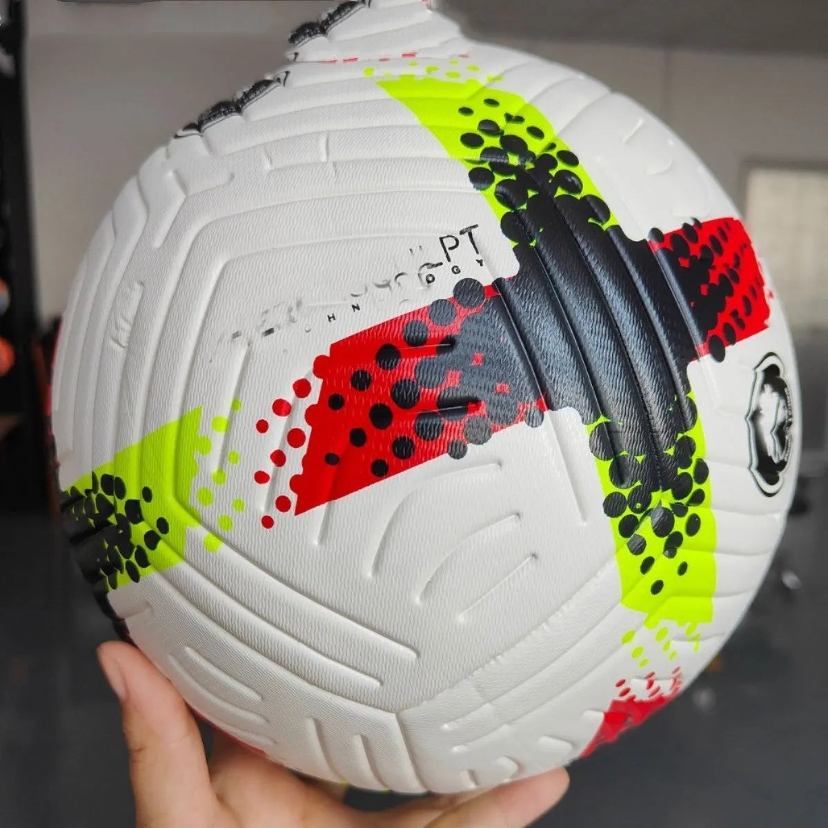 Fluorescent green Size 5 football with seamless thermal adhesive patches on a green pitch.