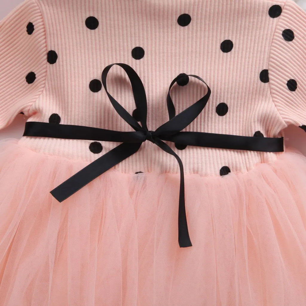 Baby girl wearing a long sleeve white lace tutu dress for a birthday or christening.