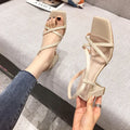 Women's white chunky heel Roman sandals with backless design and side cut-outs on a solid background.