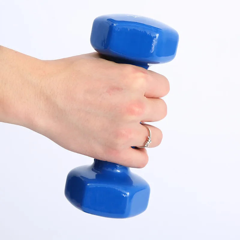 Set of bright colour plastic fitness dumbbells in various weights on a floor.