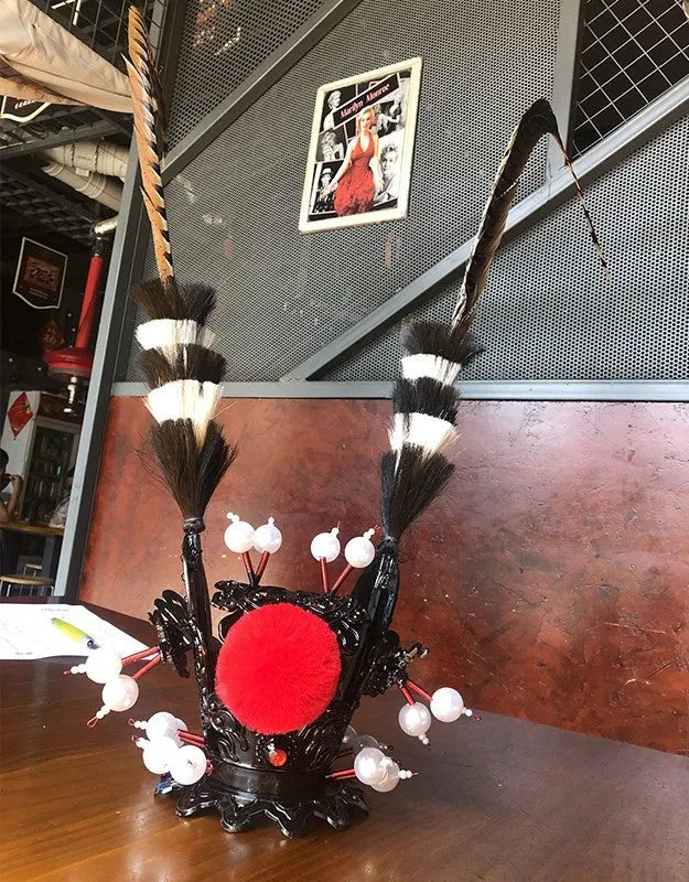 Black and gold crown with long feather plume decoration for mounting on a motorcycle helmet.