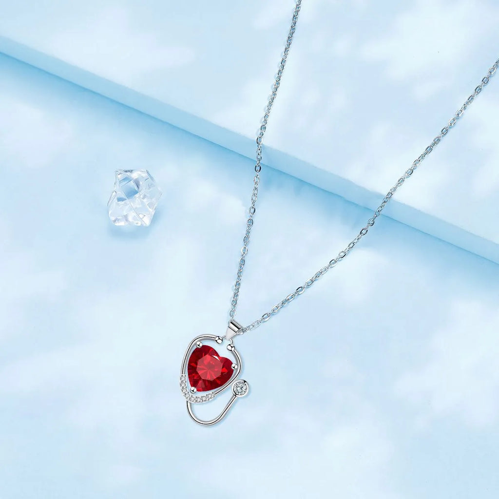Copper women's necklace with wings cross stethoscope pendant in red diamond electroplated finish.