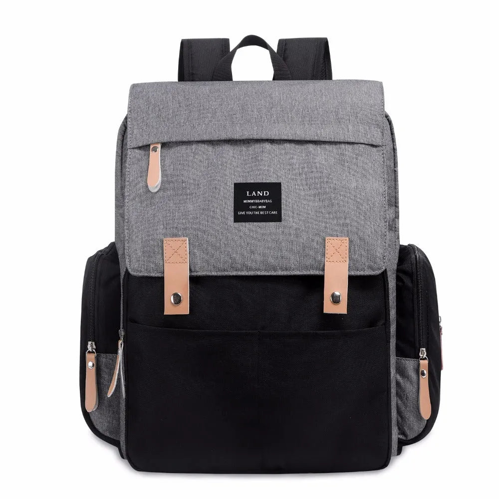 LAND Mommy large grey diaper backpack with multiple compartments and a changing mat laid out
