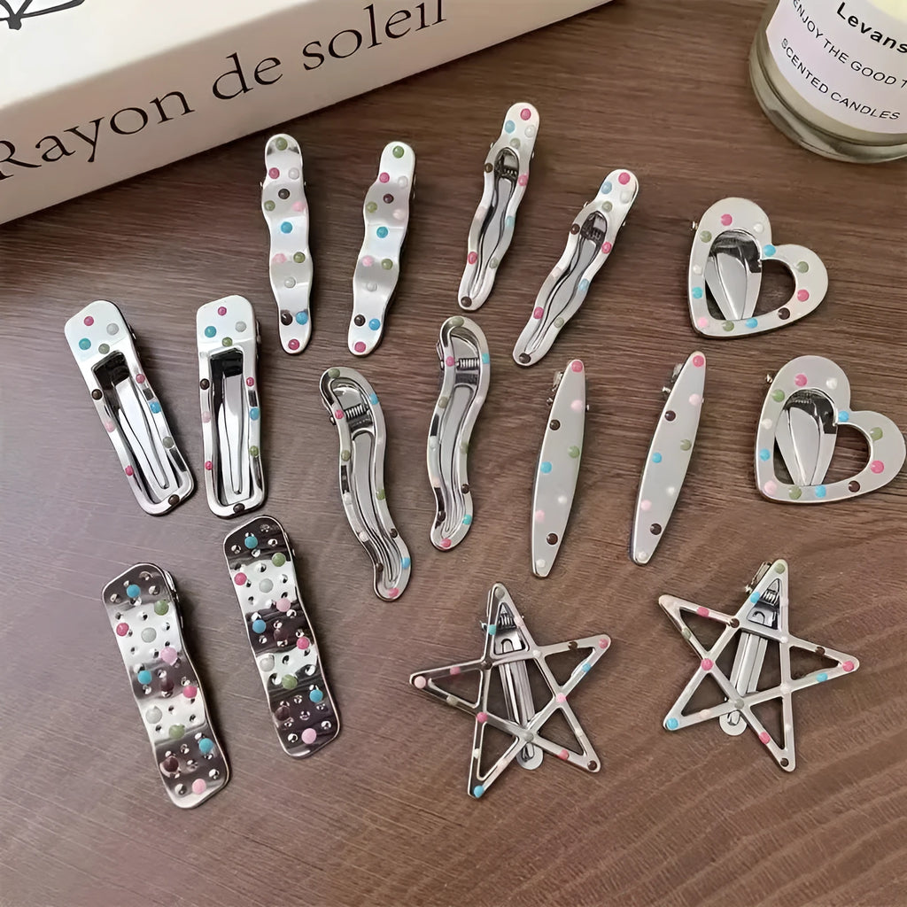 Two shiny silver metal duckbill barrettes with hollow star patterns on a plain background
