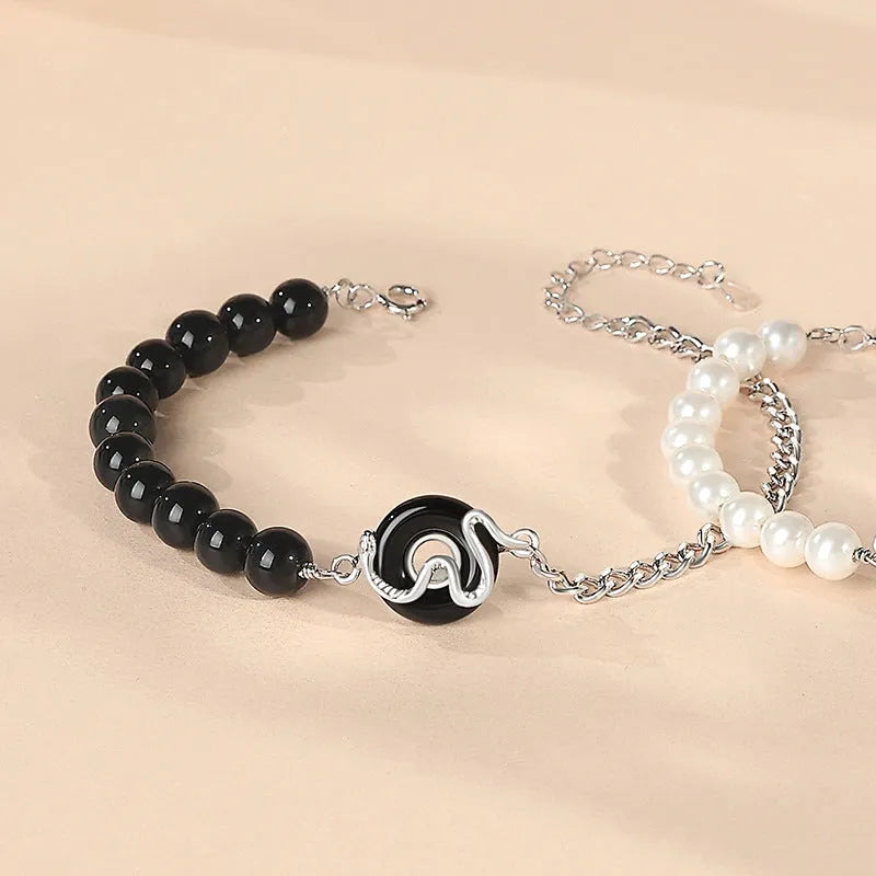 925 sterling silver bracelet with snake charm, obsidian pearl, and safe buckle closure on a wrist.