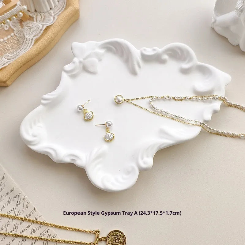European Baroque style gypsum jewellery display plate with rings and earrings on a dressing table