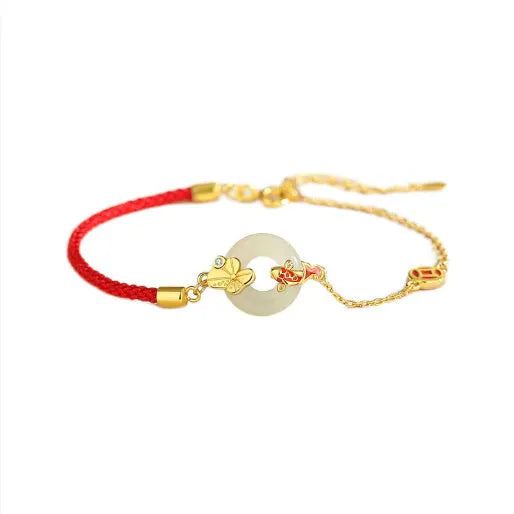 Women's silver bracelet with gold peace buckle and koi fish charm on a red rope.