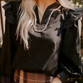 Black women's long sleeve blouse with V-neck, contrast stitching, and ruffle sleeve details.
