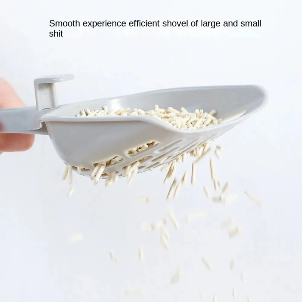 Grey plastic cat litter scoop with attached stand, shown next to a litter box.
