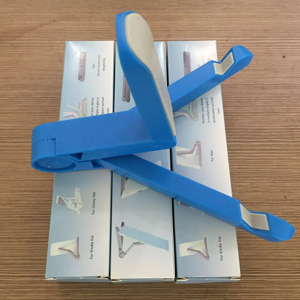 Black foldable tablet holder stand supporting a smartphone in landscape mode on a desk.