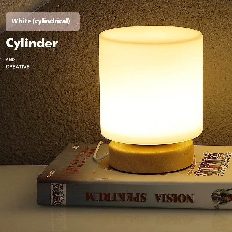 Nordic solid wood base USB table lamp with a white geometric shade on a wooden table.