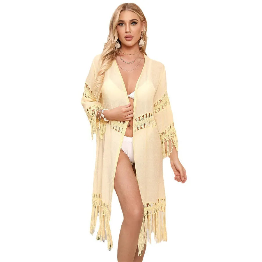 Yellow hand-crocheted women's cardigan with tassels, laid flat as a beach cover-up.