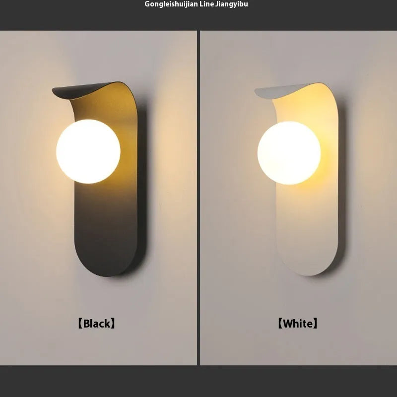 Modern minimalist black wall lamp with iron shade and LED light on a bedroom wall