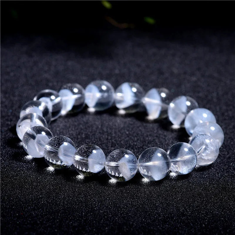 Women's white crystal bracelet with a ghost pyramid charm and Ruyi symbol, showing round beads.
