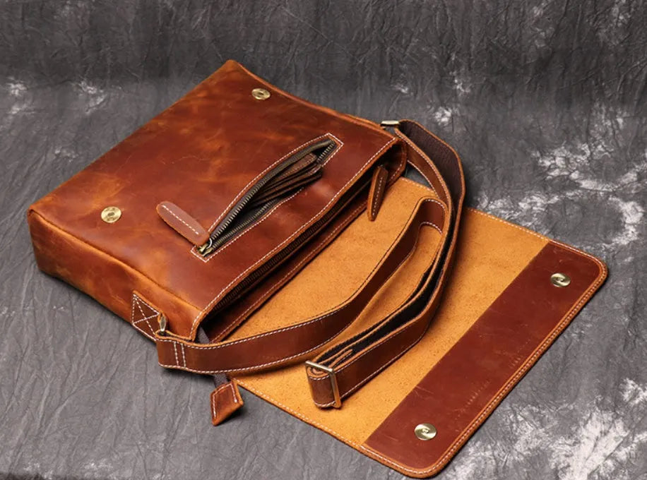 Men's vintage brown cowhide medium messenger bag showing front flap and long shoulder strap.