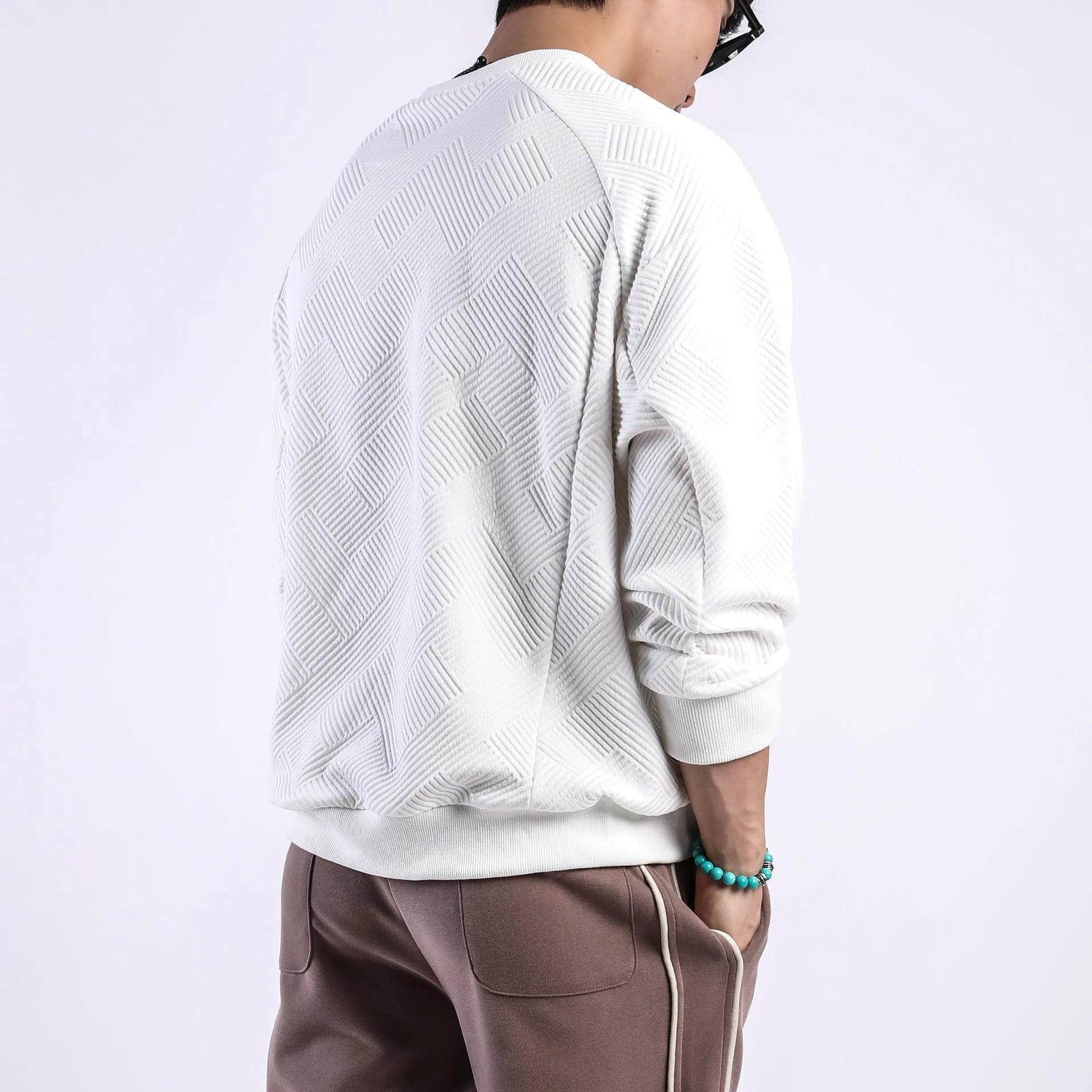 Men's loose fit long-sleeved twill jacquard sweater in a solid colour on a hanger