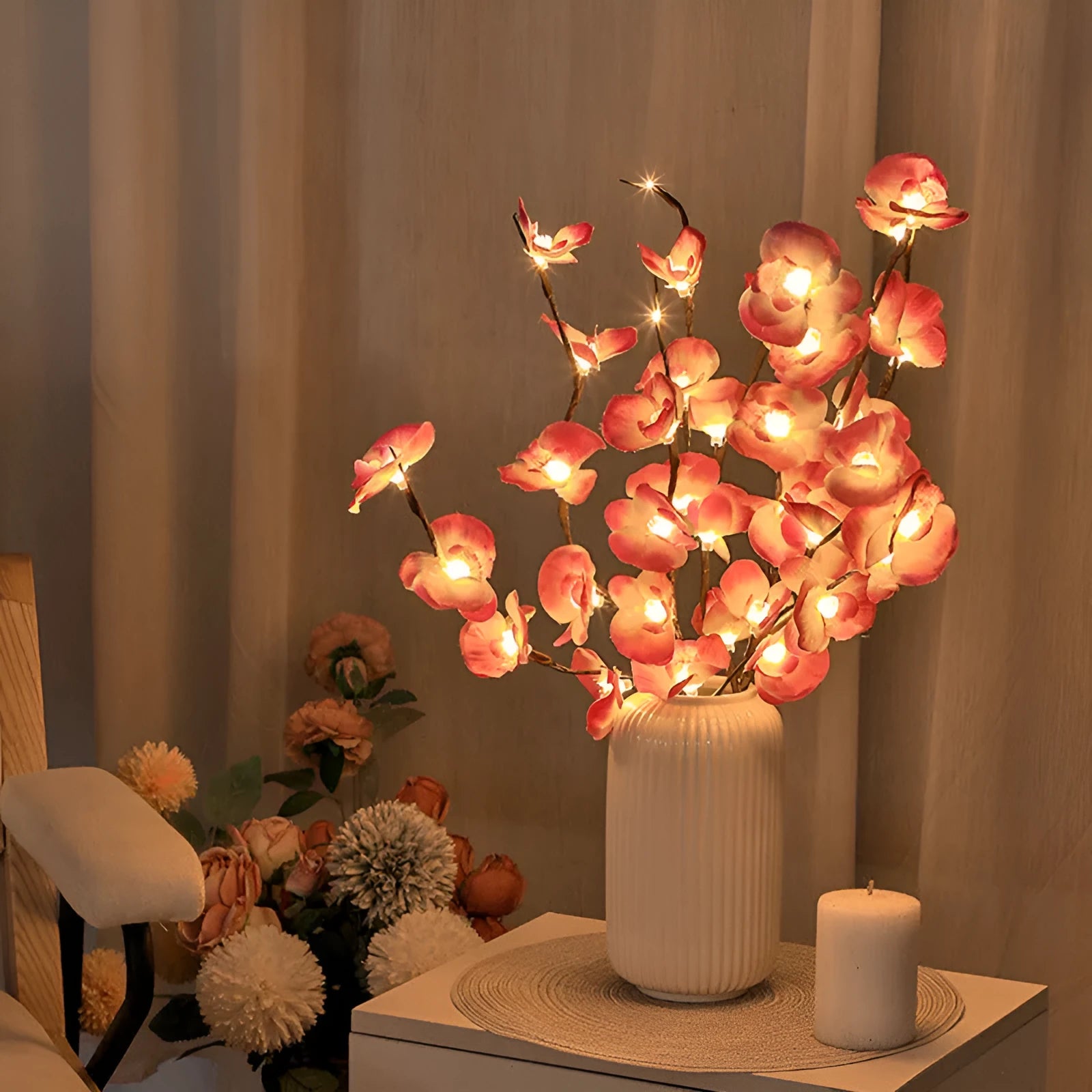 Pink artificial Phalaenopsis orchid branch LED decorative light, 65cm tall, on a bedside table.