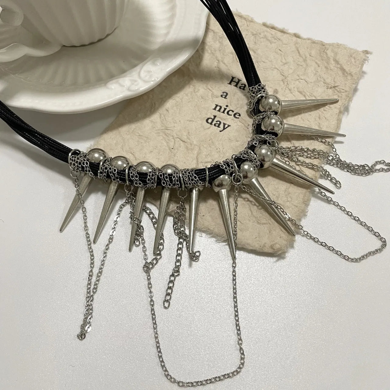 Leather necklace with round beads, a tassel, and silver rivet details on a white background.