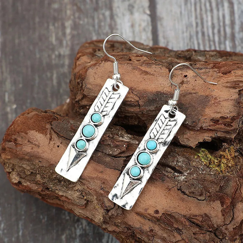 Silver geometric long strip earrings with inlaid turquoise details on a white background.
