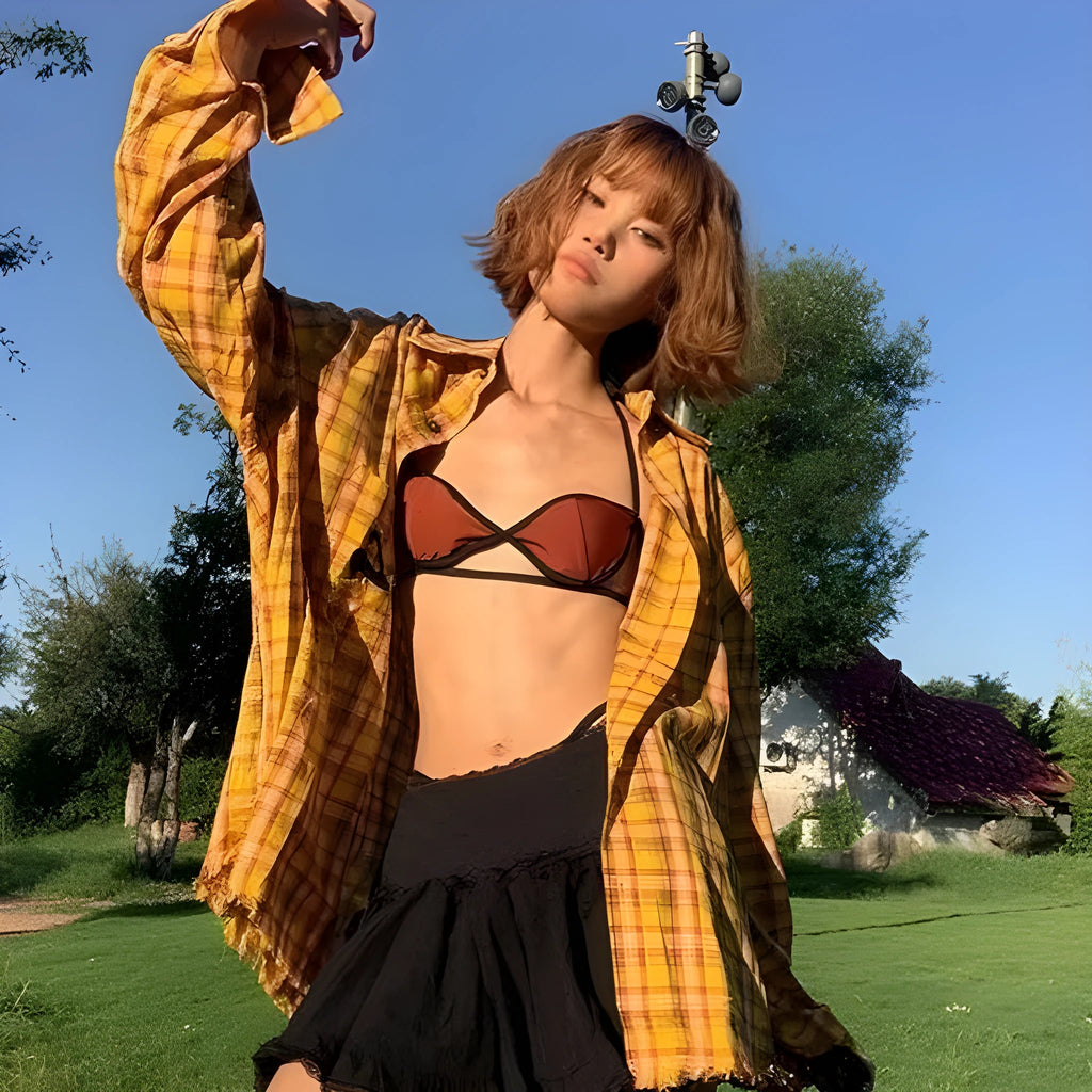 A loose yellow and black plaid shirt with a cardigan style, shown on a hanger.