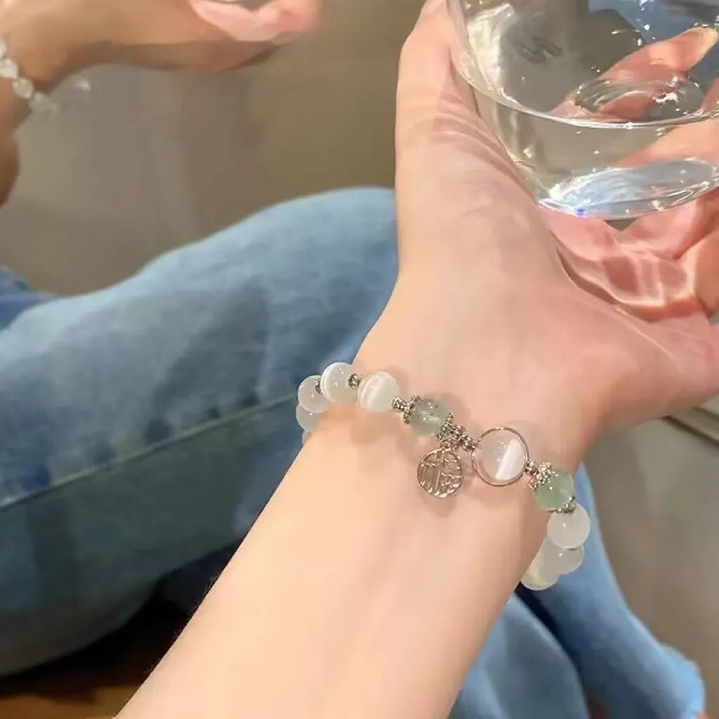 Close-up of a drop-shaped glass butterfly bracelet with round coloured beads on a wrist.