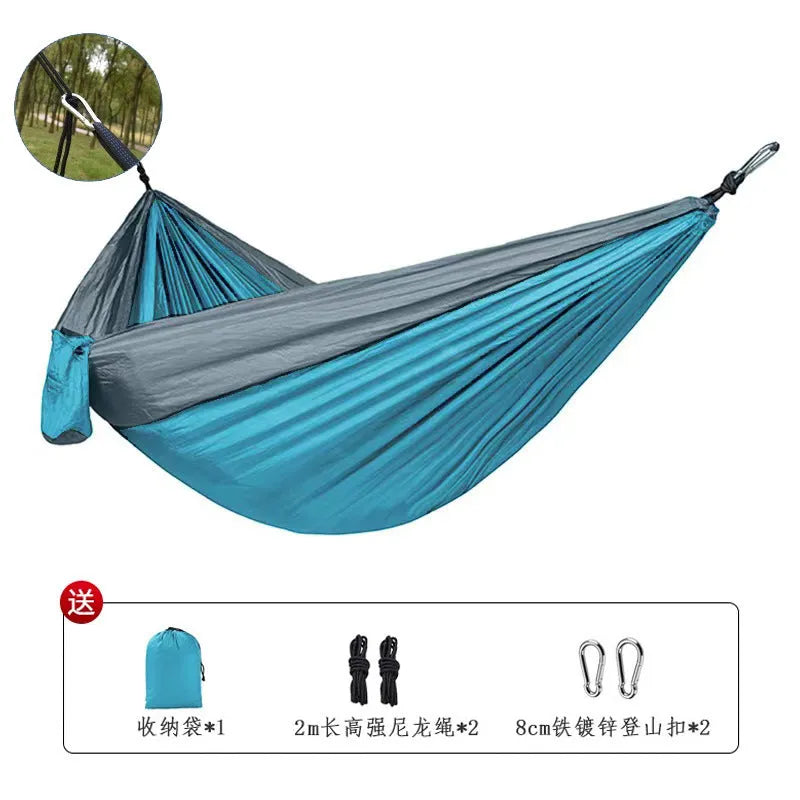 Blue parachute nylon camping hammock hung between two trees, showing its full 270cm length.
