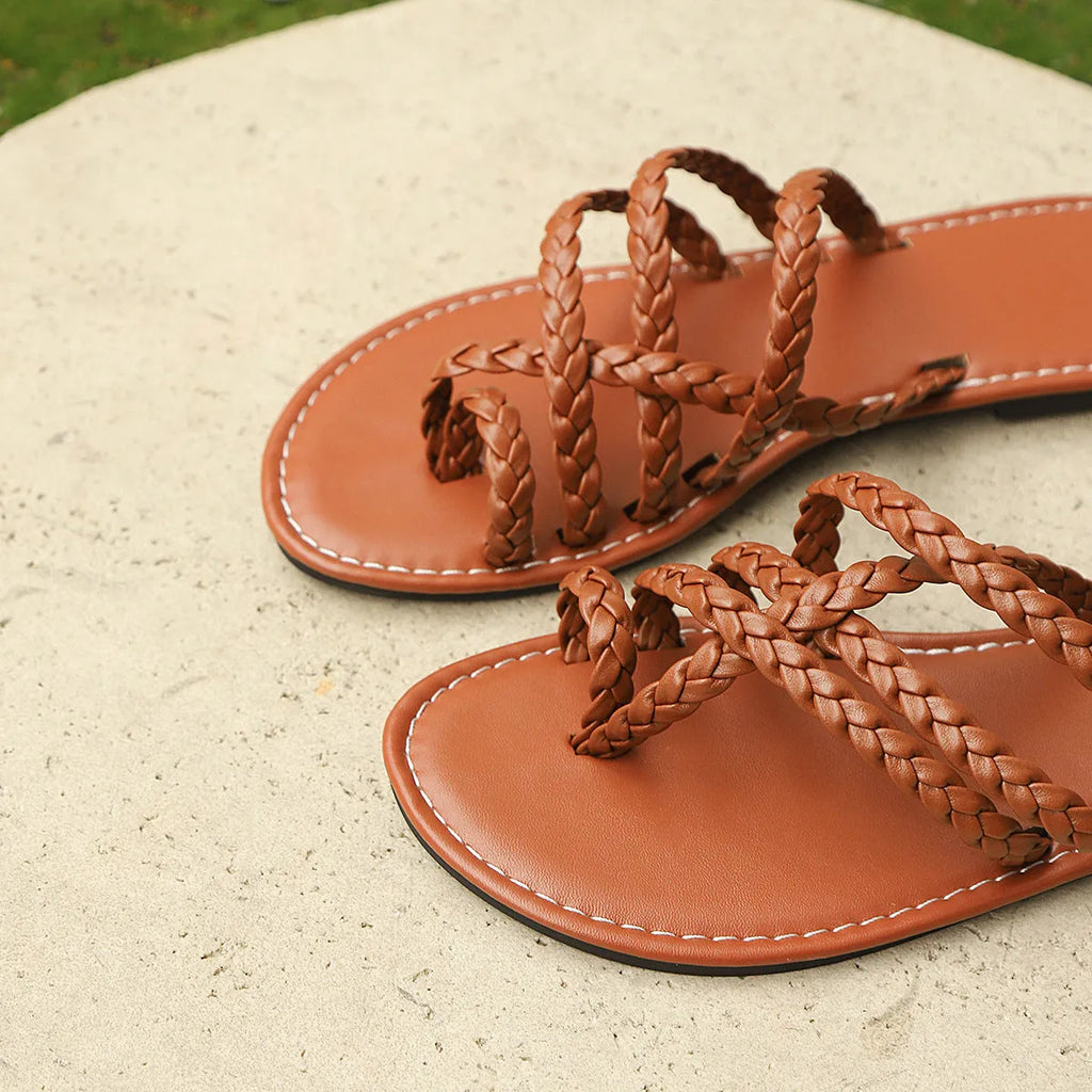 Women's brown woven clip-toe flat Roman sandal on a white background.