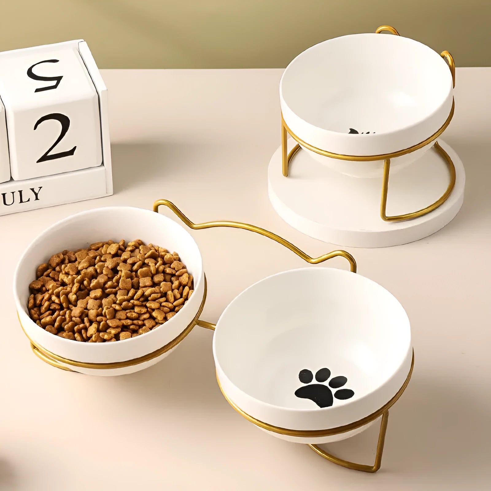 White ceramic pet bowl with cat footprints design in a black iron frame.