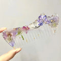 Small glossy resin hair comb with a reflective mirror finish, shown in one of three colour options.