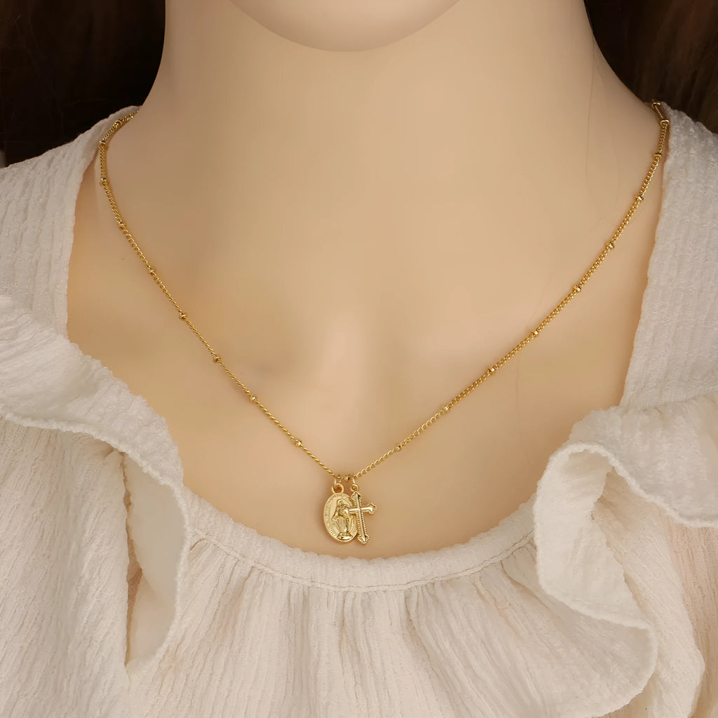 Gold-coloured geometric cross pendant necklace featuring the Virgin Mary, on a matching chain.