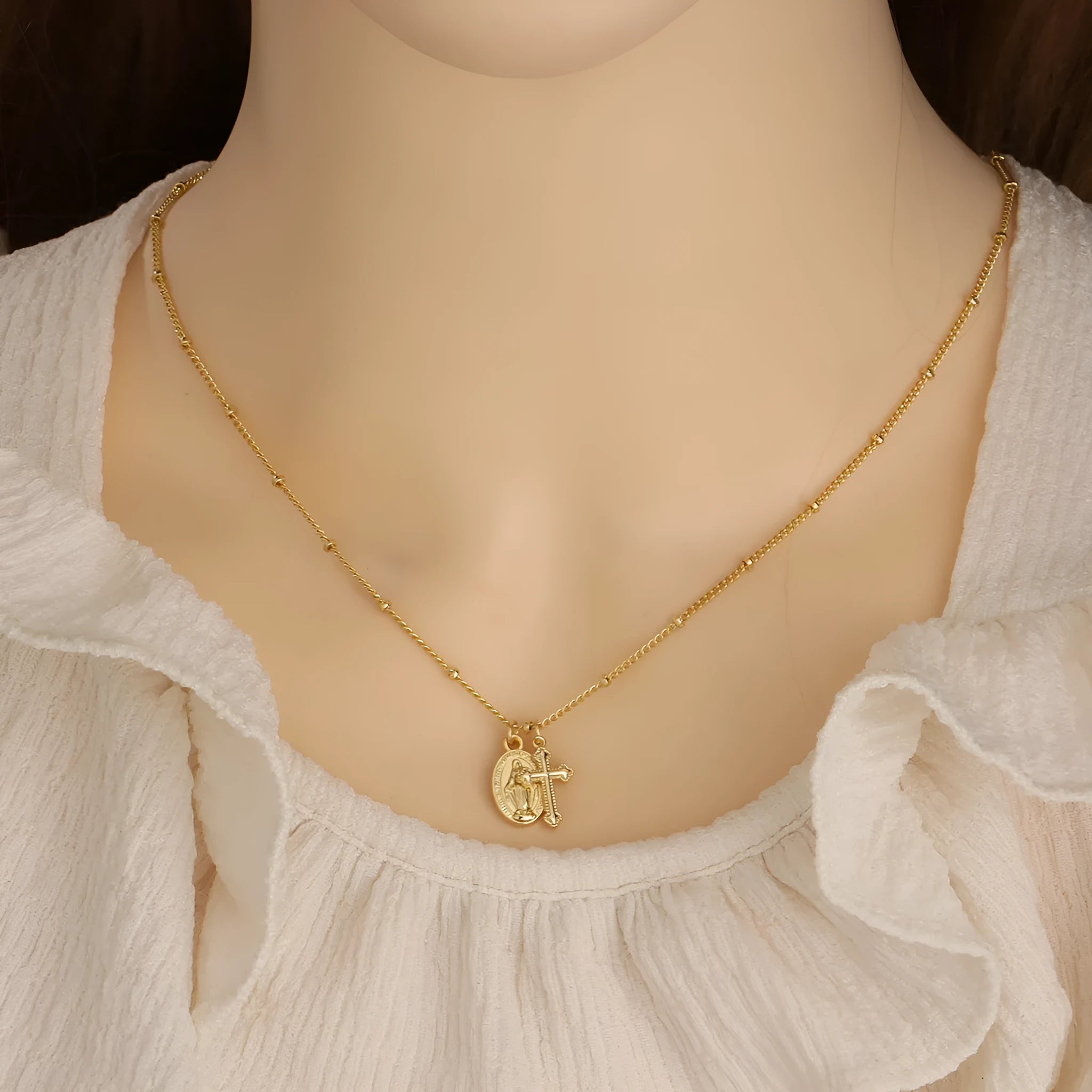 Gold-coloured geometric cross pendant necklace featuring the Virgin Mary, on a matching chain.