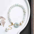 Natural jade bracelet with peace buckle fastener and white pearl accents, geometric pendant design