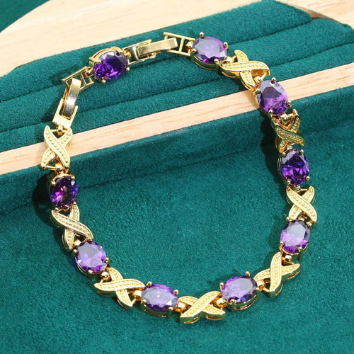Gold-coloured jewellery set with coloured cubic zirconia stones, showing necklace, earrings, ring, and bracelet.