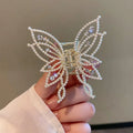 Butterfly-shaped hair clip with metal alloy construction and decorative rhinestone or pearl elements