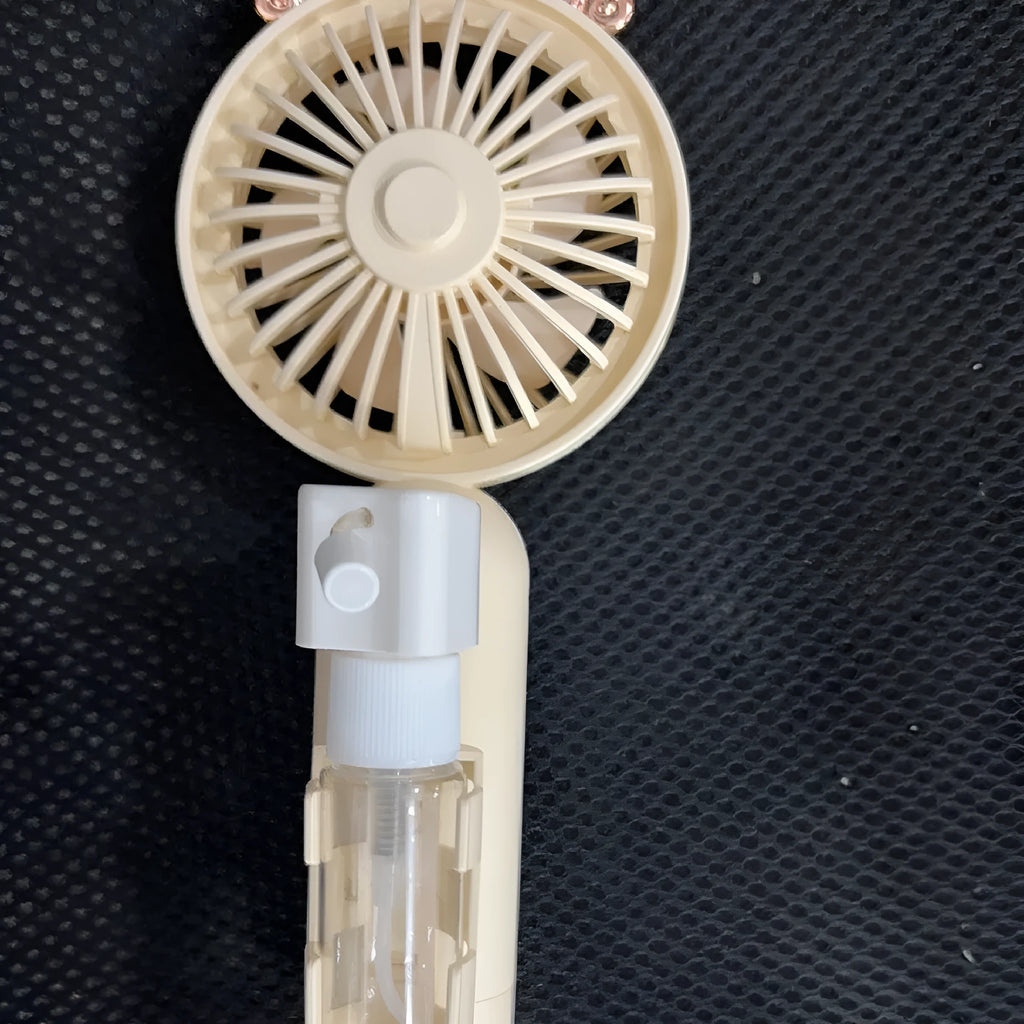 USB handheld personal fan in apricot colour with plastic nozzle, shown with charging cable.