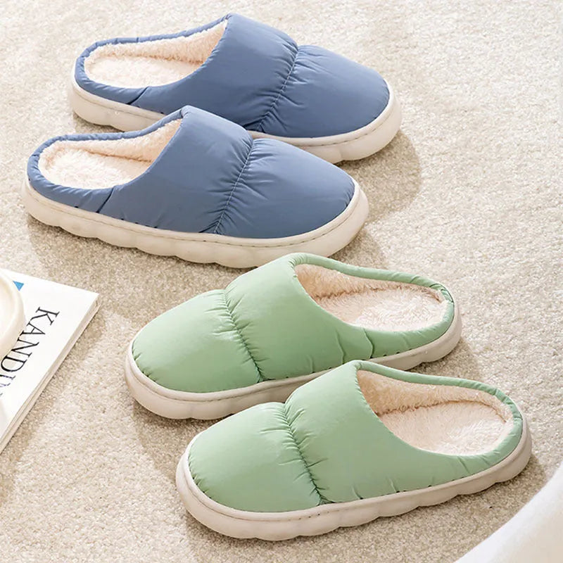Pair of thick-soled indoor slippers in blue with a wrapped toe, low heel, and artificial plush lining.