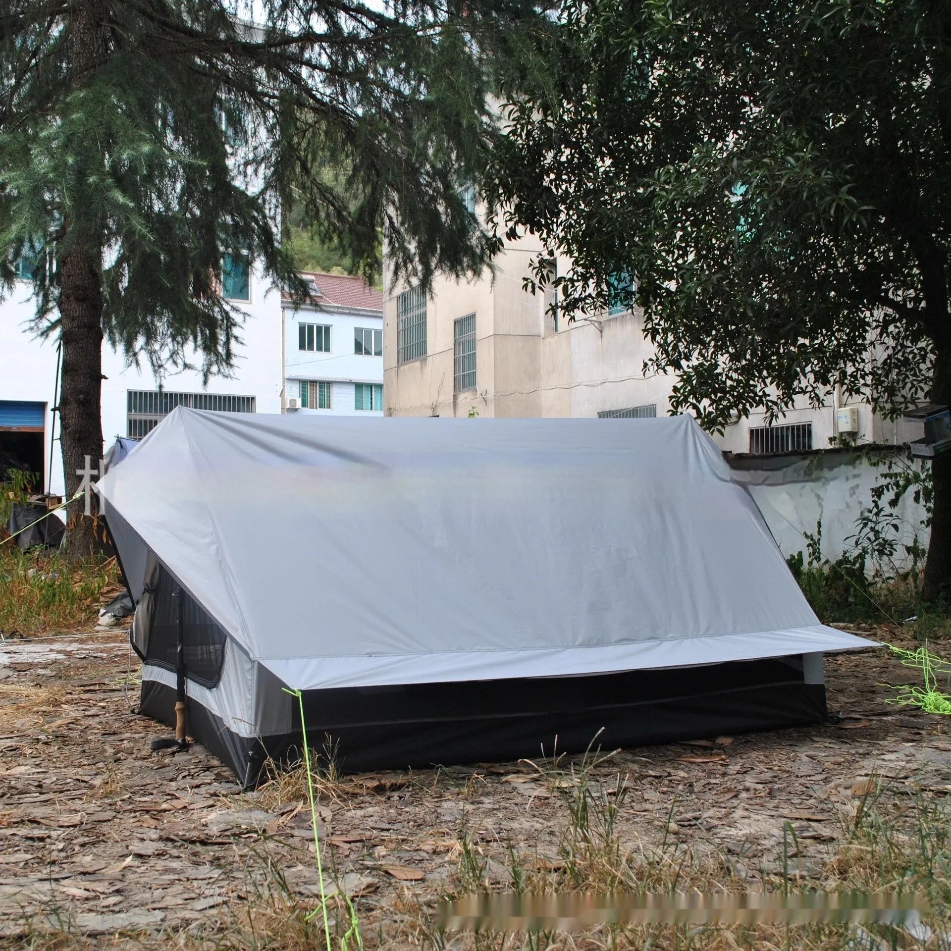 Brown or white A-line pole-free cabin tent for hiking, shown packed and pitched.