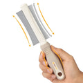 White double-sided pet grooming brush with curved comb and deshedder on an ergonomic anti-slip handle