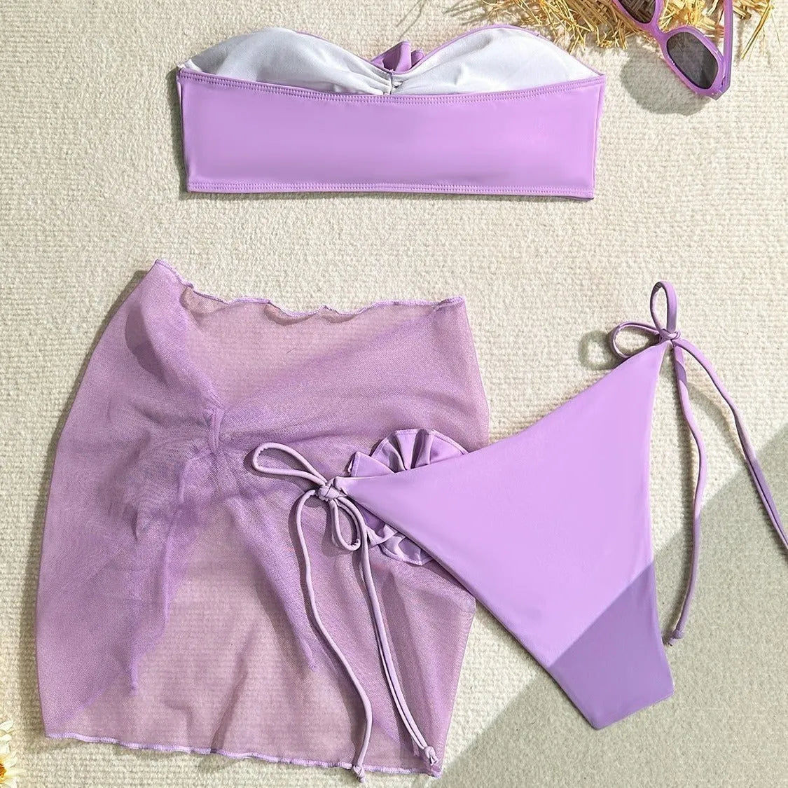 Blue women's tube top swimsuit with a large 3D tied flower, matching pants, and a skirt laid flat.
