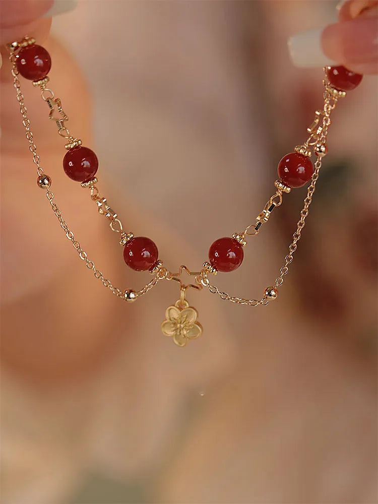Handmade red agate double layer bracelet with floral peach blossom design on a white background.