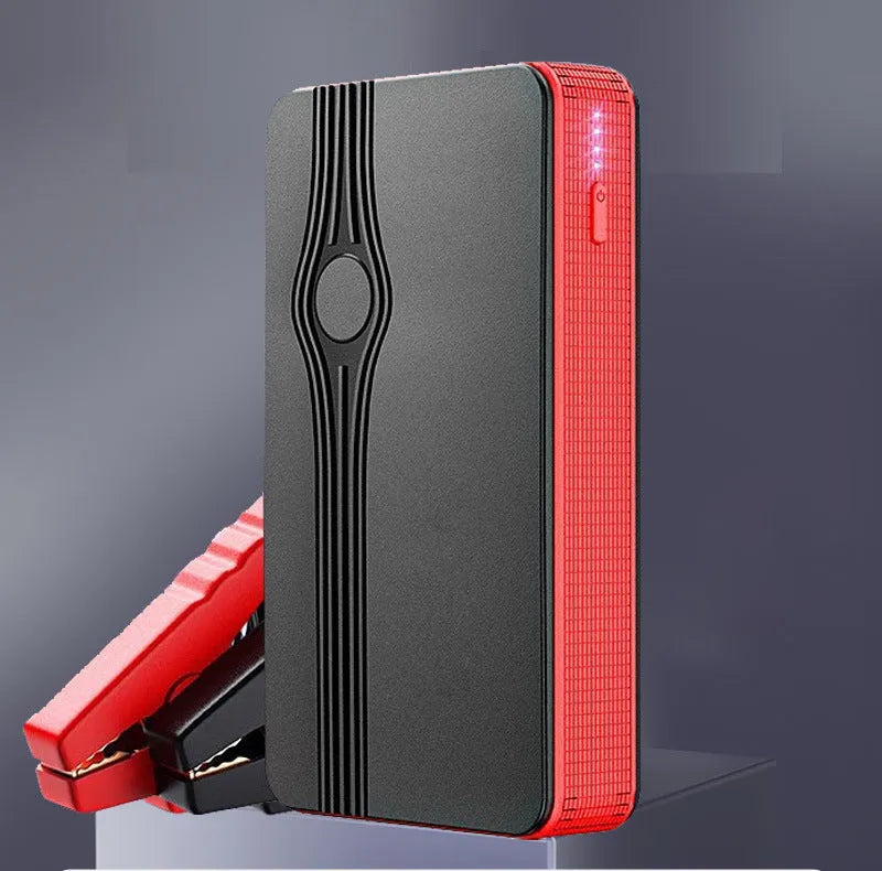 Red K4-E car jump starter power bank with display, shown next to a data cable on a dark surface.