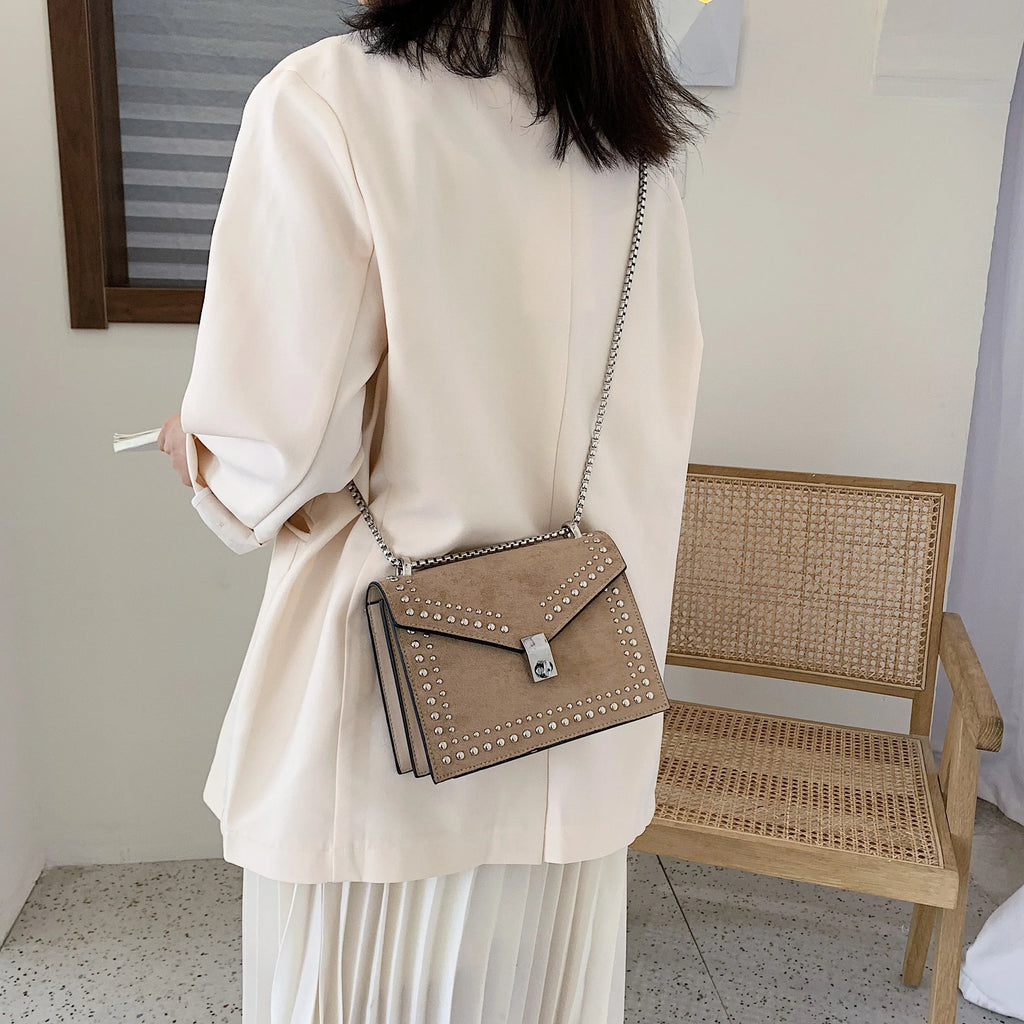 Small PU shoulder messenger bag for women with lock detail, chains, and rivet decoration on a soft flap.