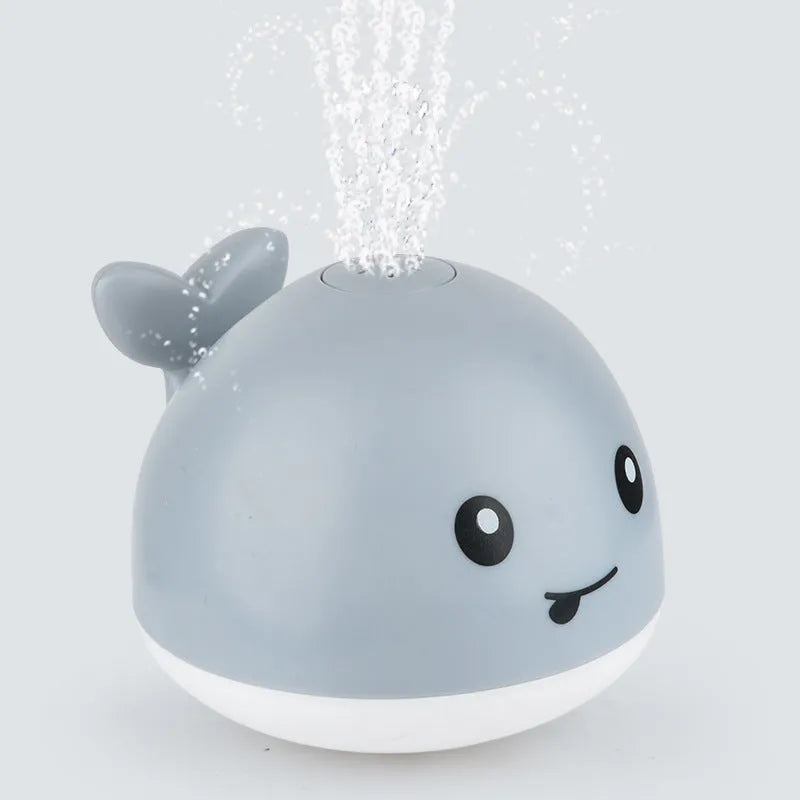 Blue and white whale bath toy with water spray and flashing lights for baby sensory play