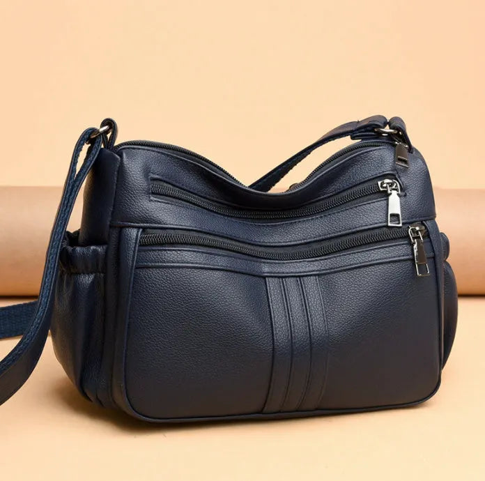 Genuine leather horizontal square messenger bag in black with contrast stitching and a front slit pocket.