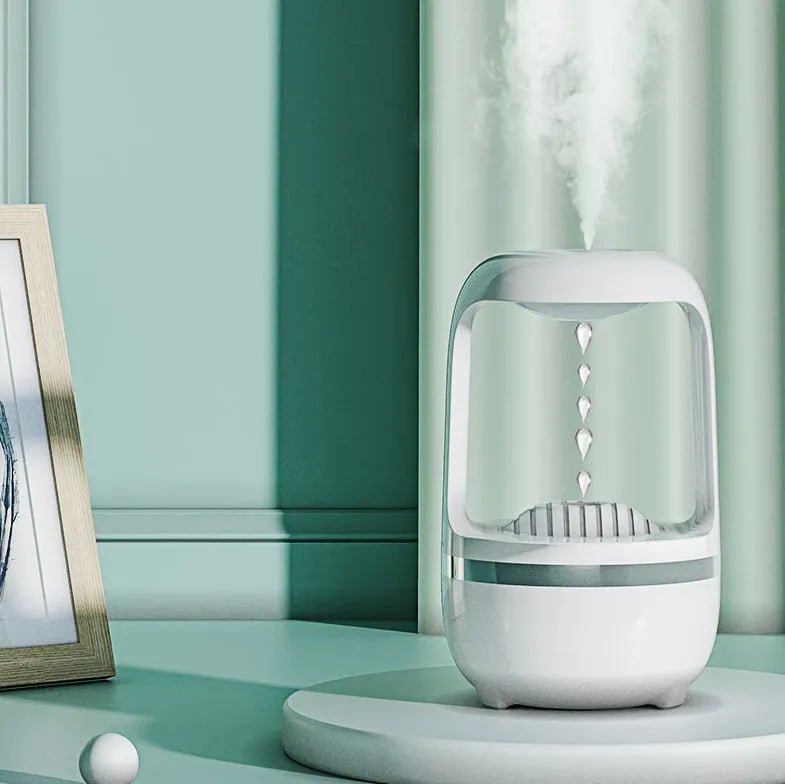 White anti-gravity humidifier showing floating water droplets on a desk next to a USB cable.