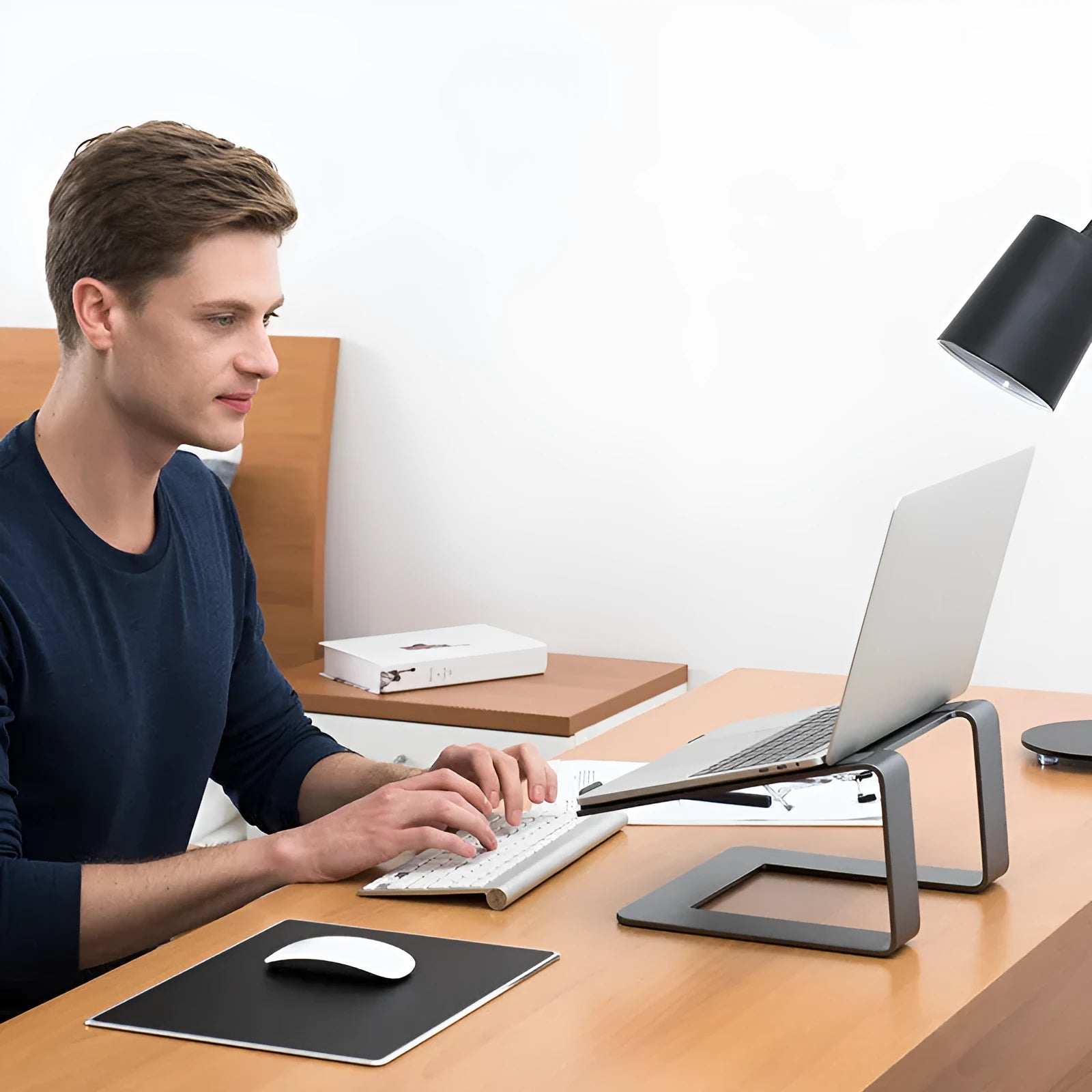Black aluminium alloy laptop stand on a desk, showing its raised platform and dimensions.